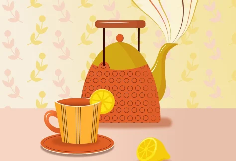 Steaming teapot, cup of tea with a slice of lemon on a table with pretty floral wallpaper in the background